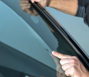 Person points to small chip on a car windshield